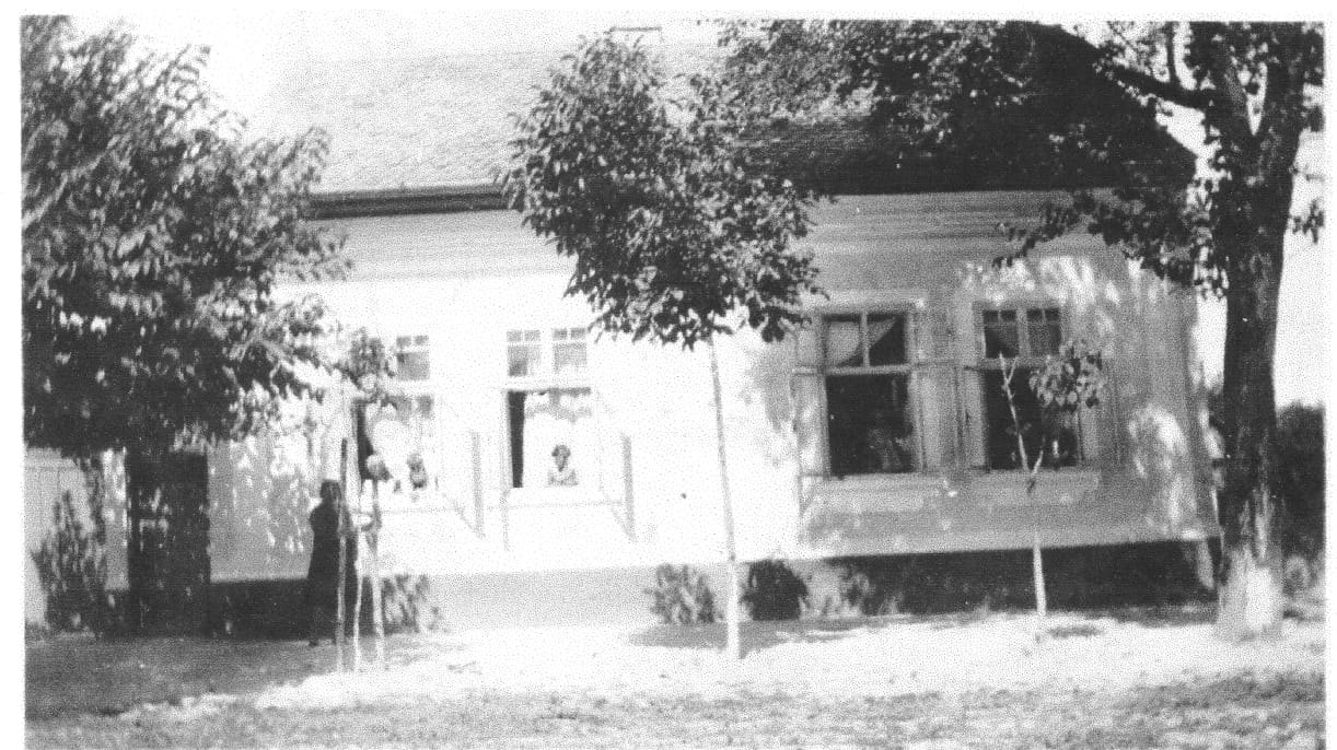La casa de la familia en Parabutsch: blanca, de una planta, con árboles frutales al frente